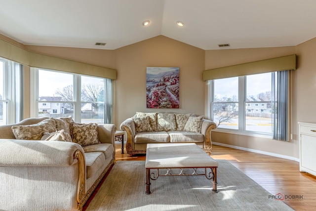 living area featuring baseboards, visible vents, vaulted ceiling, and wood finished floors