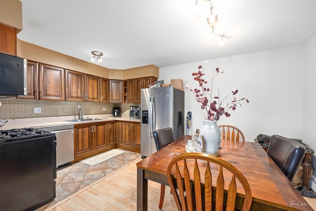 kitchen featuring stainless steel appliances, sink, light wood-type flooring, and decorative backsplash