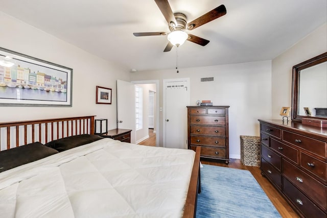 bedroom with dark wood-style floors, visible vents, and ceiling fan