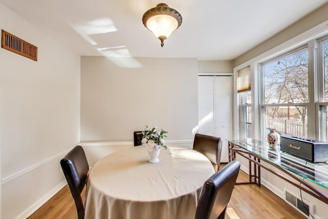 dining room featuring light wood-style flooring, visible vents, and baseboards