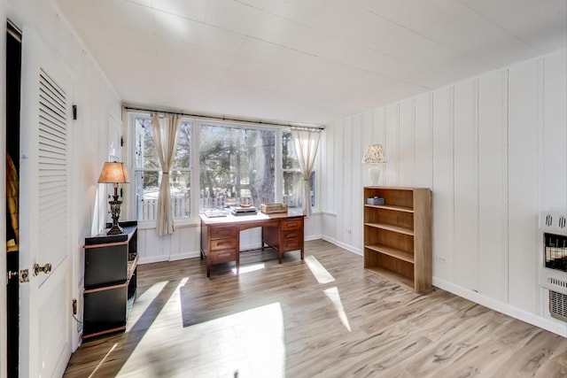 office space featuring baseboards, heating unit, and wood finished floors