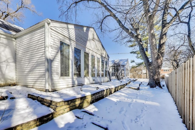 snow covered property with fence