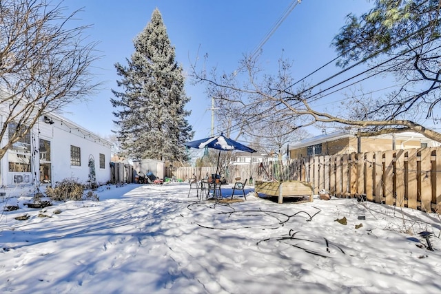 snowy yard featuring a fenced backyard