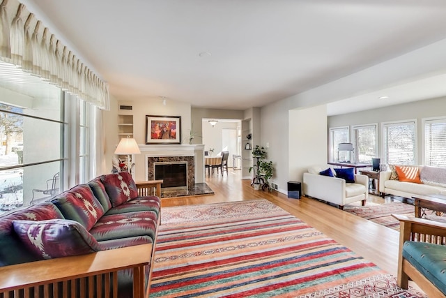 living room featuring light wood-style floors, baseboards, and a premium fireplace