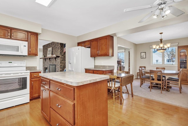 kitchen with light hardwood / wood-style flooring, ceiling fan with notable chandelier, a center island, white appliances, and pendant lighting