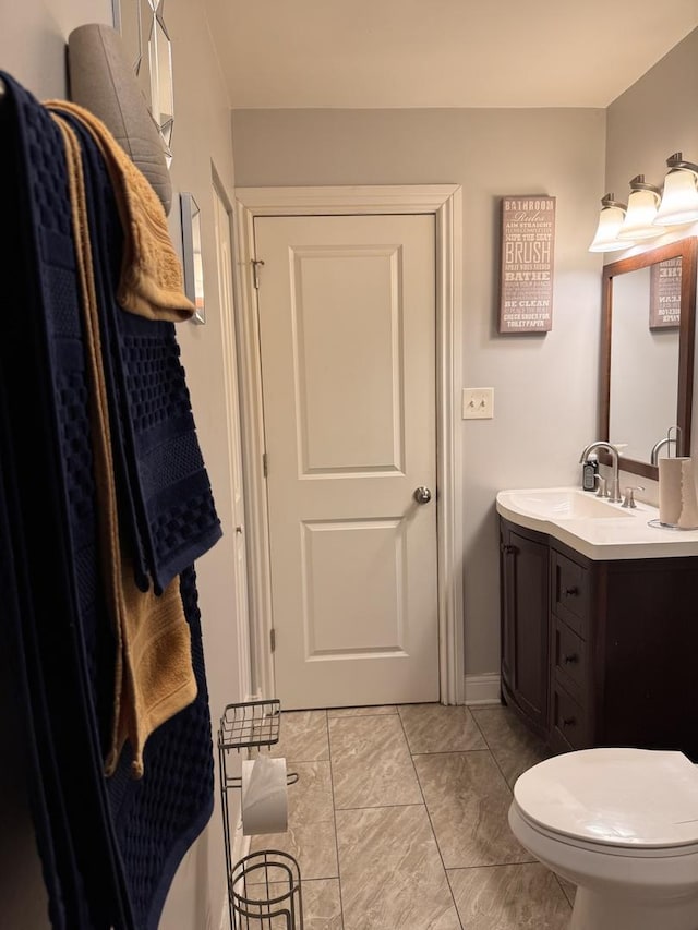 bathroom with toilet, marble finish floor, and vanity