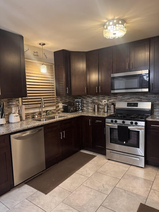 kitchen with stainless steel appliances, a sink, dark brown cabinets, decorative backsplash, and decorative light fixtures