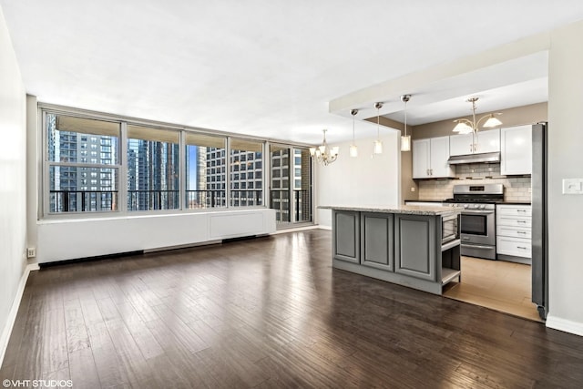 kitchen with a view of city, decorative light fixtures, stainless steel appliances, gray cabinetry, and under cabinet range hood