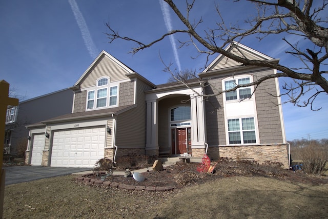 view of front of home featuring a garage, stone siding, and driveway