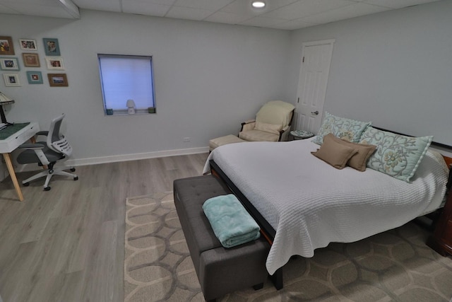 bedroom with a drop ceiling and light hardwood / wood-style flooring