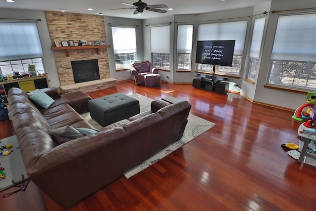 living room featuring hardwood / wood-style floors, a stone fireplace, and ceiling fan