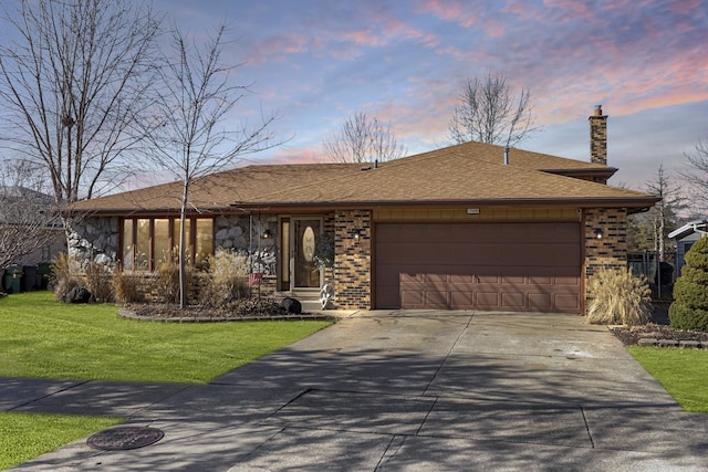 ranch-style house featuring concrete driveway, brick siding, a yard, and a chimney