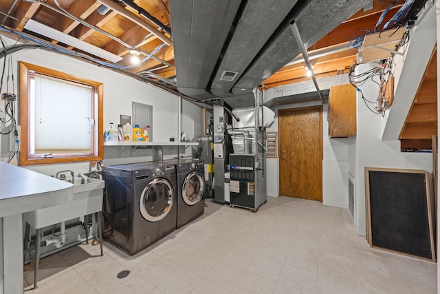 washroom featuring washing machine and dryer, visible vents, and heating unit