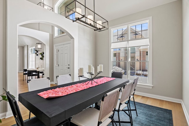 dining room featuring wood-type flooring, a high ceiling, and a notable chandelier