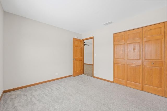 unfurnished bedroom with a closet and light colored carpet