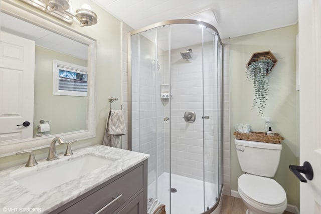 bathroom with a shower with door, vanity, and toilet