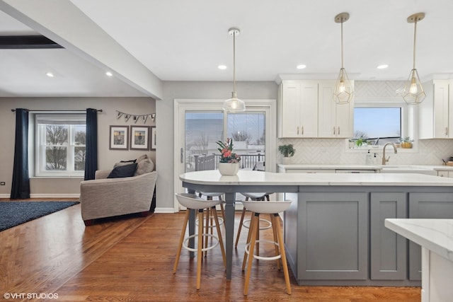 kitchen with white cabinetry, decorative light fixtures, light stone counters, and gray cabinetry