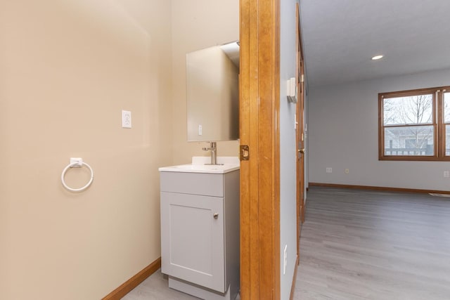 bathroom featuring baseboards, recessed lighting, wood finished floors, and vanity