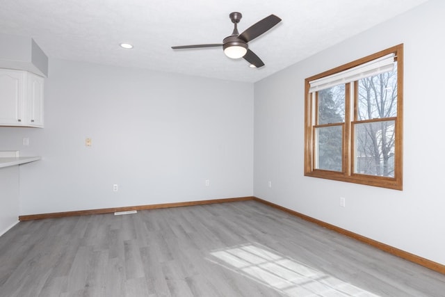 unfurnished room with baseboards, a ceiling fan, and light wood finished floors