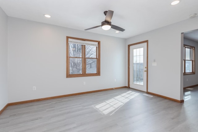 spare room featuring baseboards, visible vents, a healthy amount of sunlight, and wood finished floors