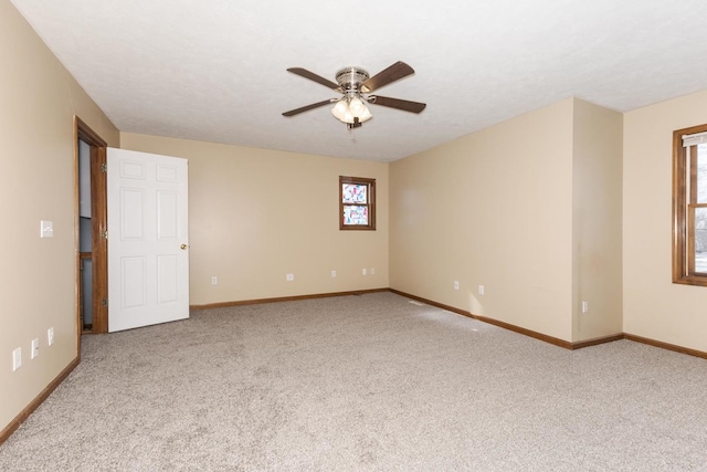 carpeted spare room featuring baseboards and ceiling fan