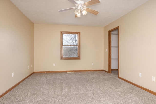 carpeted empty room with baseboards and a ceiling fan