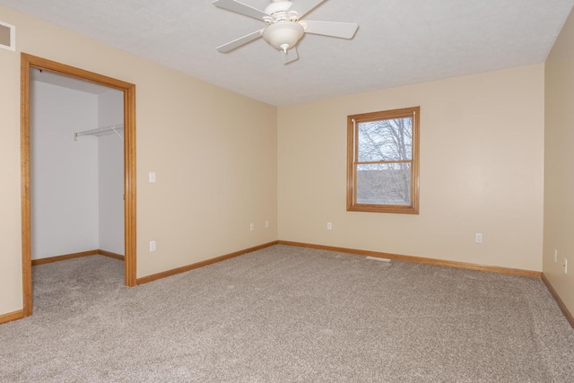 unfurnished bedroom featuring carpet floors, baseboards, a walk in closet, and a closet