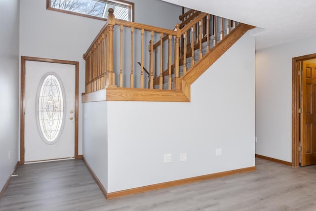 foyer featuring baseboards, stairs, and wood finished floors