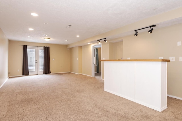 spare room with bar, light colored carpet, rail lighting, baseboards, and recessed lighting