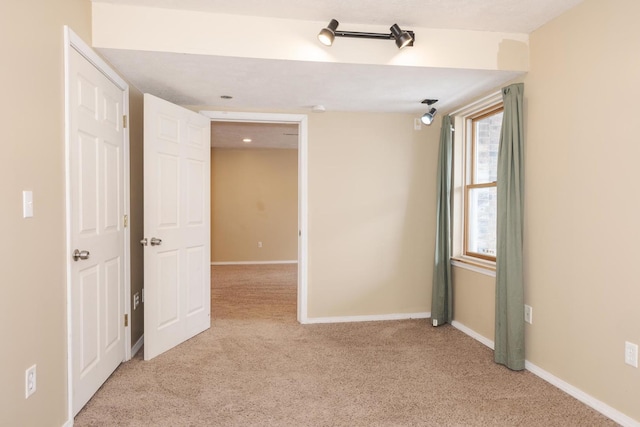 unfurnished room with baseboards and light colored carpet