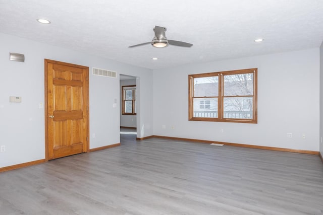 empty room featuring light wood-style floors, baseboards, a ceiling fan, and visible vents