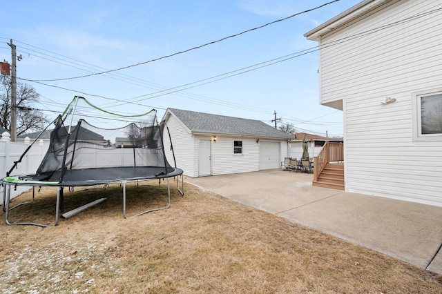 exterior space with an outbuilding, a trampoline, a garage, a yard, and a patio area