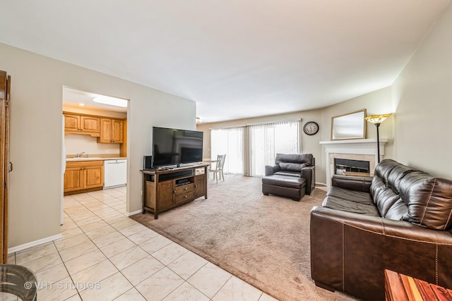 living room featuring a tiled fireplace, sink, and light colored carpet