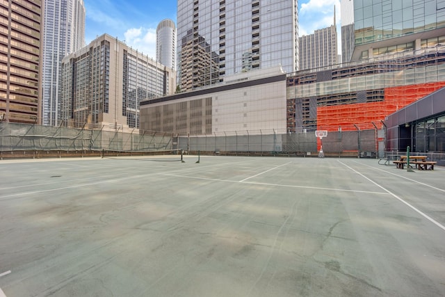 view of sport court featuring fence and a city view