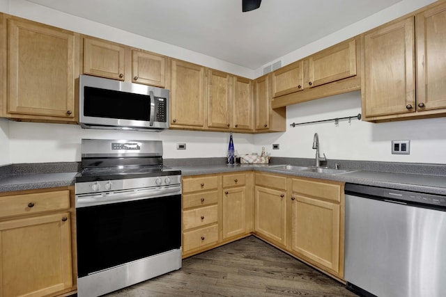 kitchen with stainless steel appliances, dark countertops, dark wood-style flooring, and a sink