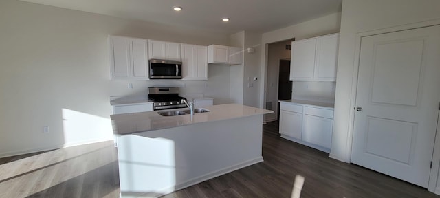 kitchen with stainless steel appliances, sink, an island with sink, and white cabinets