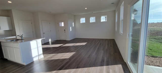 kitchen featuring white cabinetry, dark hardwood / wood-style flooring, a kitchen island with sink, and sink