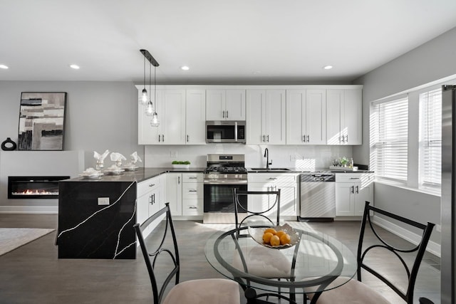 kitchen featuring sink, white cabinets, backsplash, hanging light fixtures, and stainless steel appliances