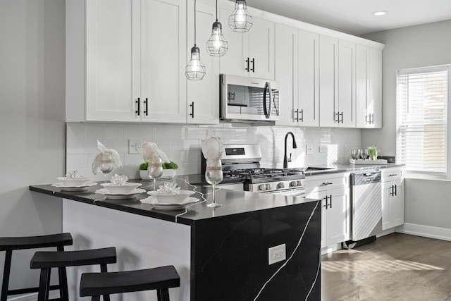 kitchen with white cabinetry, backsplash, stainless steel appliances, and a breakfast bar