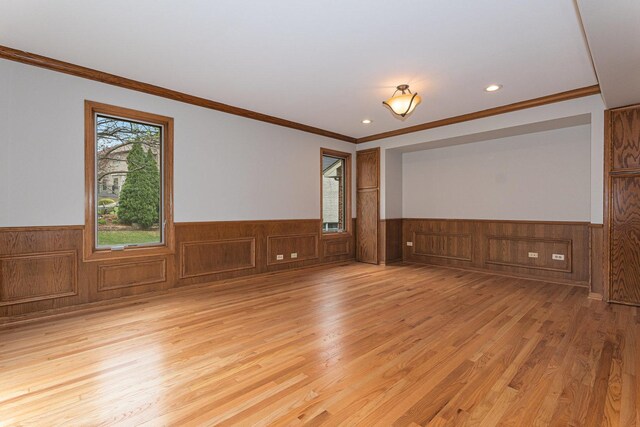 unfurnished room with crown molding, light wood finished floors, a wainscoted wall, and recessed lighting