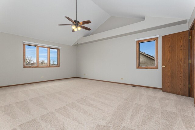 empty room featuring lofted ceiling, light colored carpet, ceiling fan, and plenty of natural light
