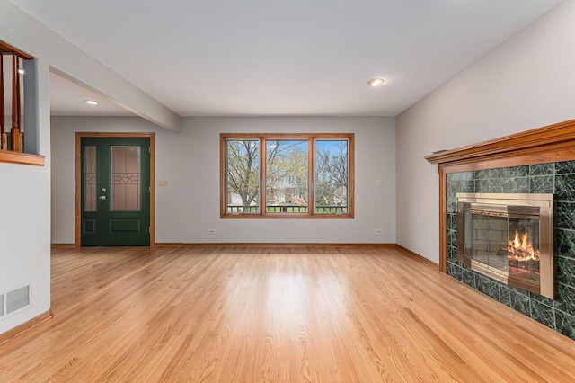 unfurnished living room with recessed lighting, a tile fireplace, visible vents, light wood-style flooring, and baseboards