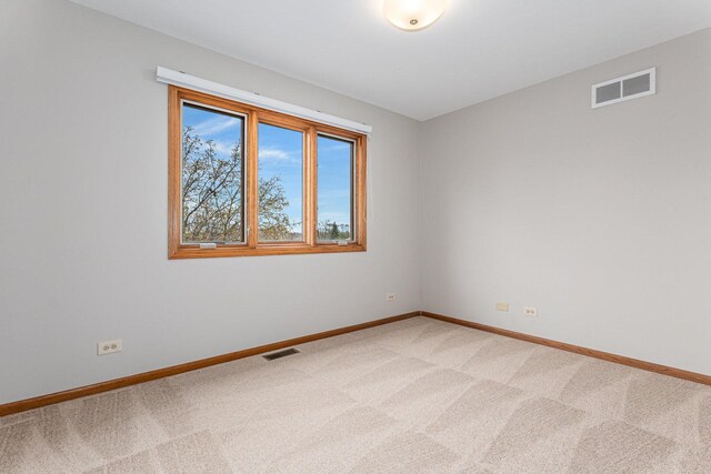 empty room with baseboards, visible vents, and light colored carpet