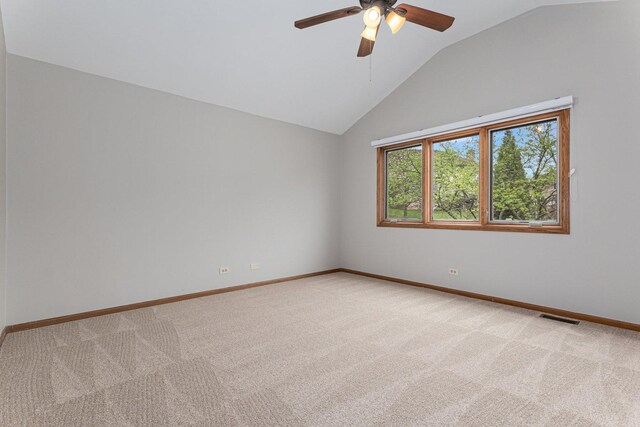 spare room featuring visible vents, a ceiling fan, vaulted ceiling, and light carpet