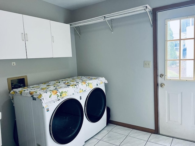 clothes washing area featuring light tile patterned floors, washer and dryer, cabinet space, and baseboards