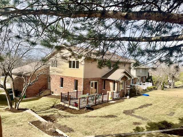rear view of property featuring a lawn, a wooden deck, and brick siding