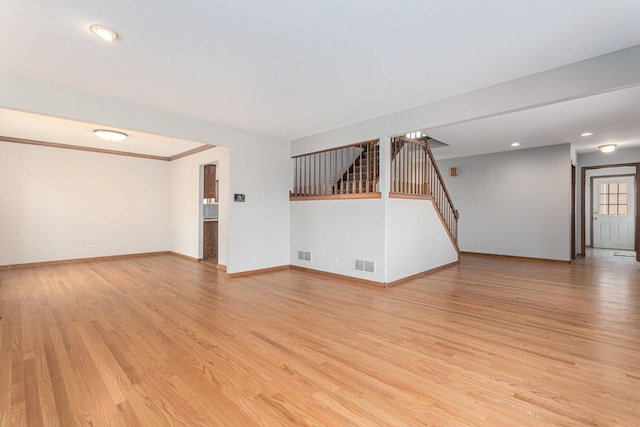 unfurnished living room with stairway, visible vents, and light wood-type flooring