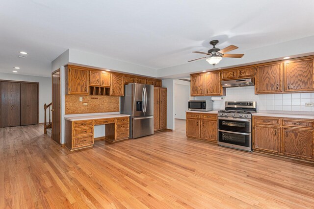 kitchen featuring under cabinet range hood, appliances with stainless steel finishes, light countertops, brown cabinets, and backsplash