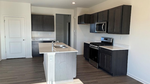 kitchen with dark hardwood / wood-style flooring, sink, an island with sink, and appliances with stainless steel finishes