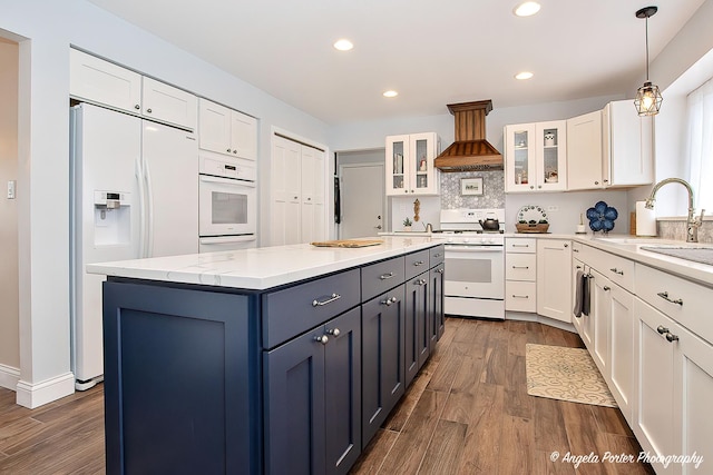 kitchen featuring white appliances, sink, custom range hood, and white cabinets